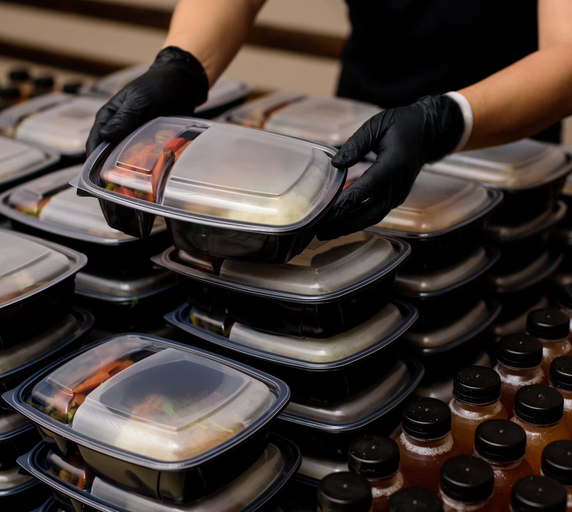 Stacked meal prep containers and bottled drinks.