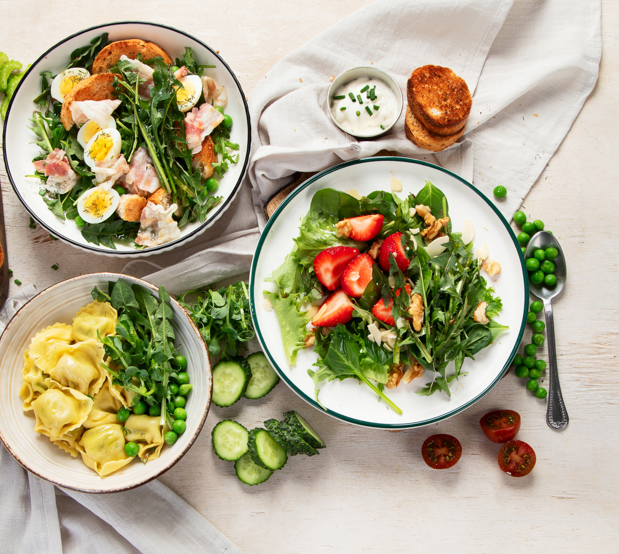 Three salads with eggs, strawberries, and tortellini.